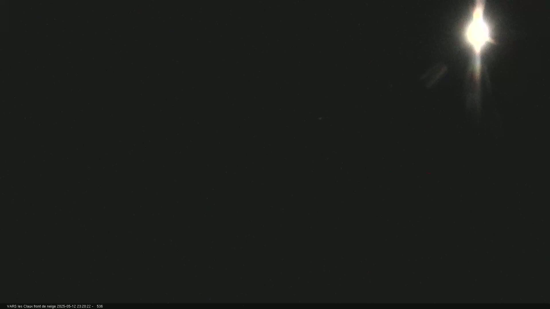 A bright light, possibly a spotlight or the moon, shines in a dark, nighttime scene.