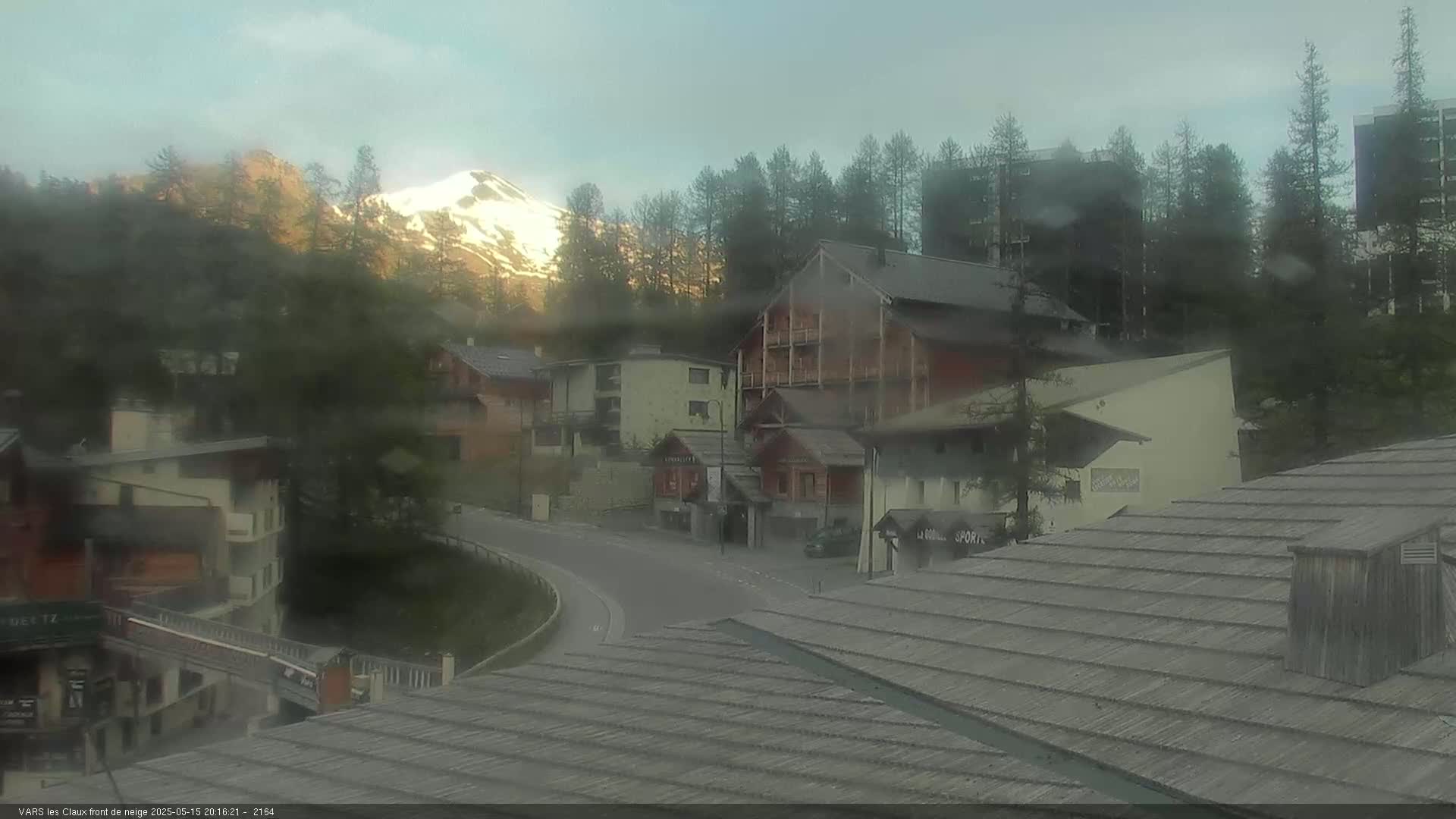 A mountain village in hazy weather, with a snow-capped mountain in the background.