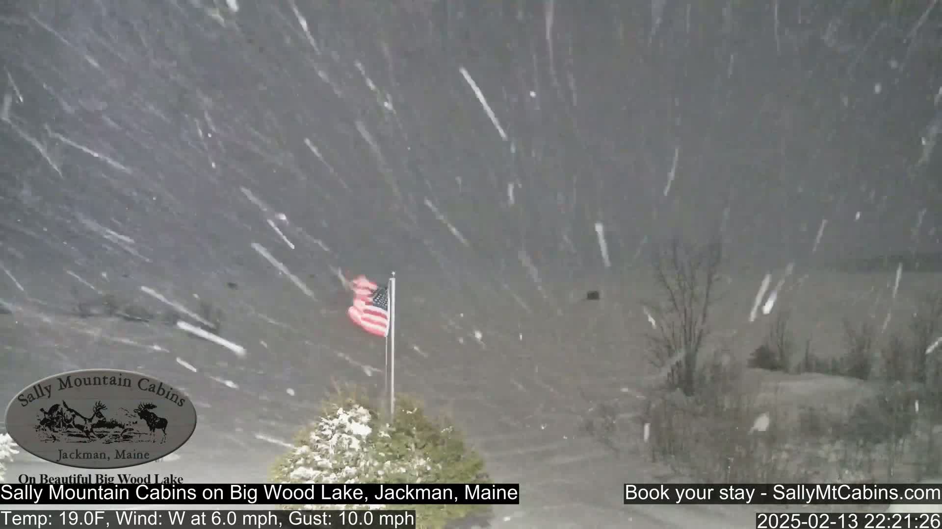 An American flag flaps in the wind amidst heavy snowfall.