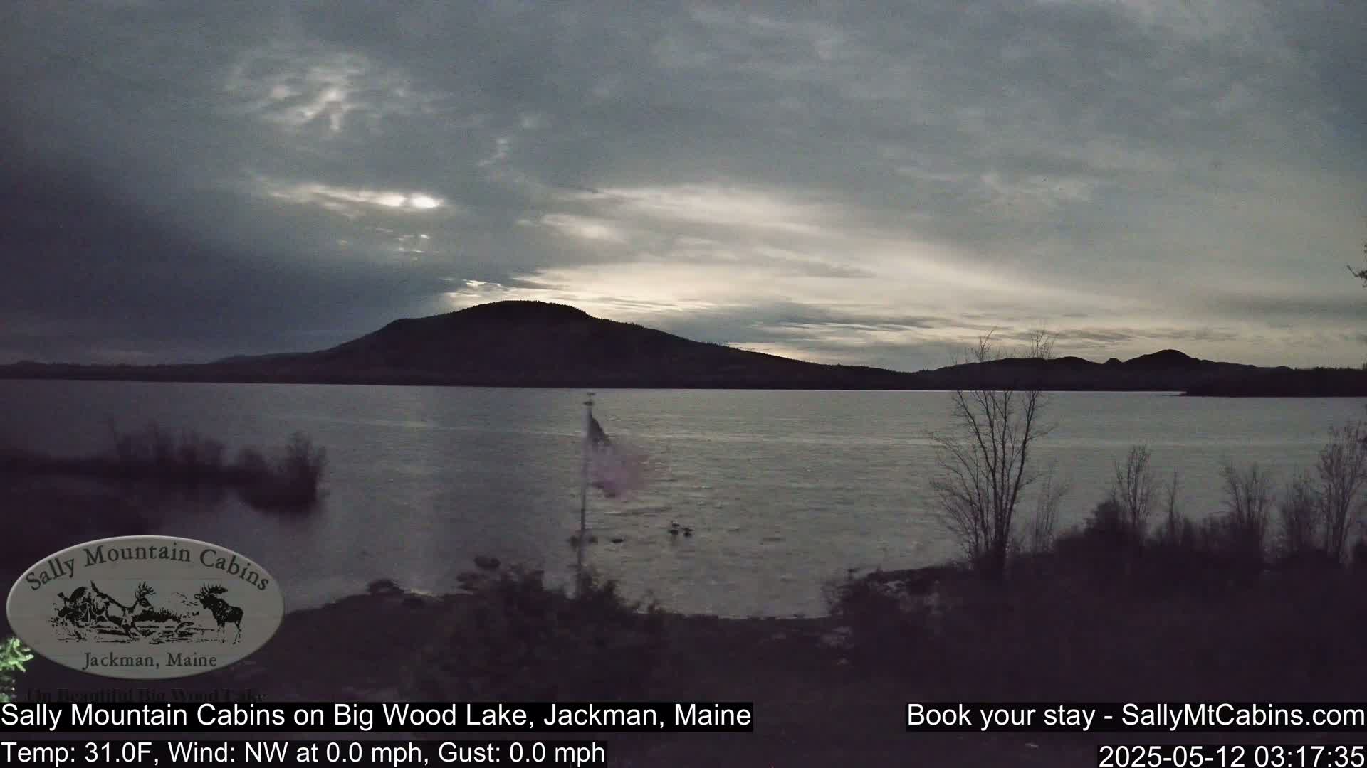 A calm, gray-sky day over a lake with a dark mountain range in the background.