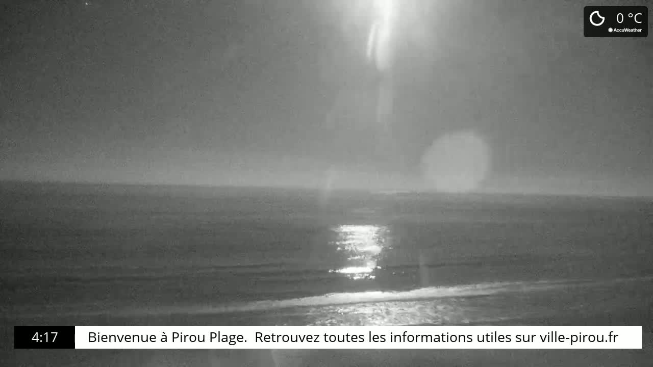 A nighttime beach scene shows a calm ocean reflecting light, under a mostly clear sky at 0°C.