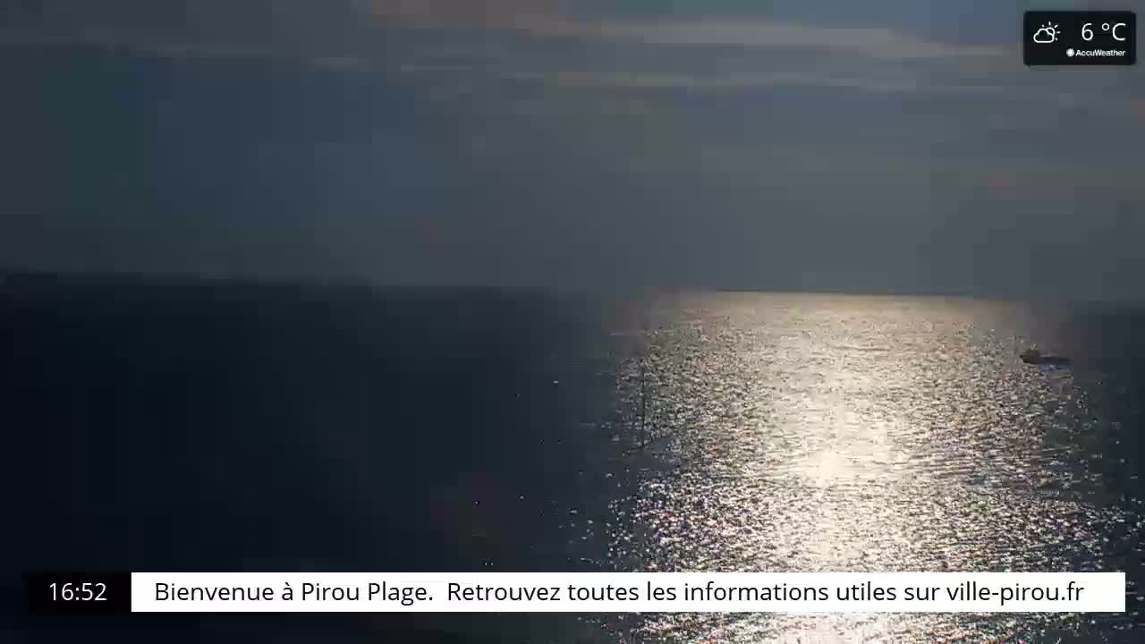 A mostly cloudy sky over a calm, sunlit sea with a single small vessel visible in the distance.
