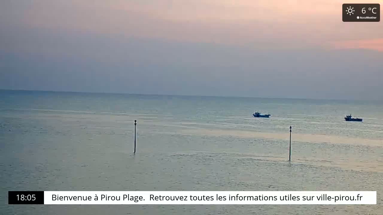 Two small boats are visible on a calm sea under a pale sunset sky.