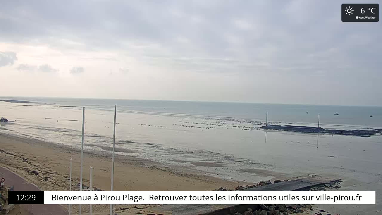 A sandy beach stretches to a calm sea under a cloudy sky.