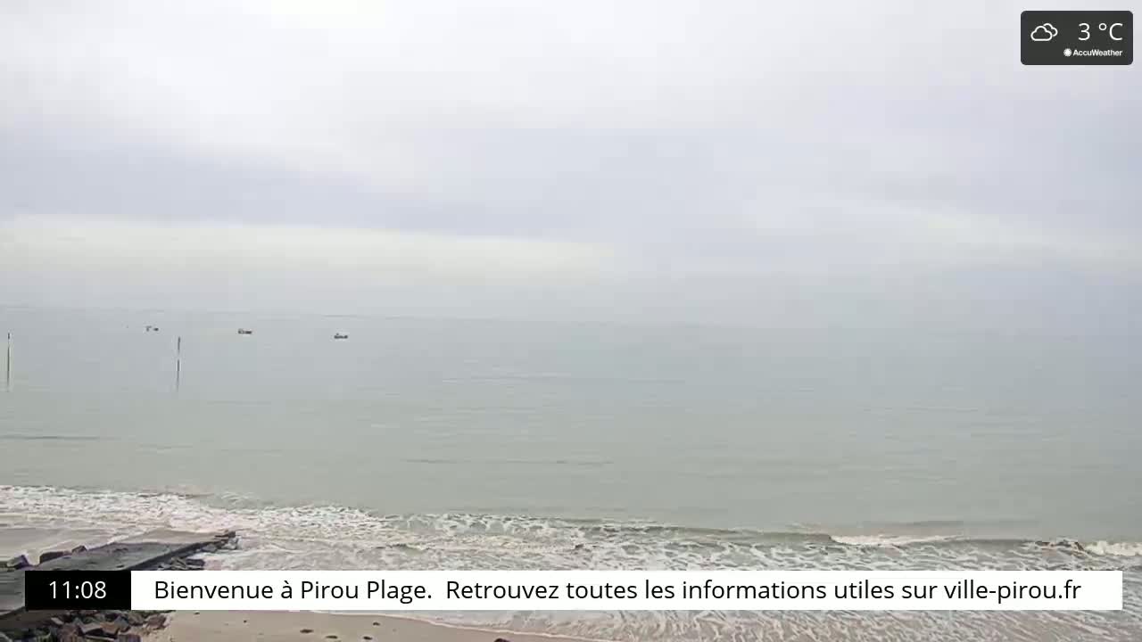 A calm, overcast ocean meets a sandy beach under a gray sky.