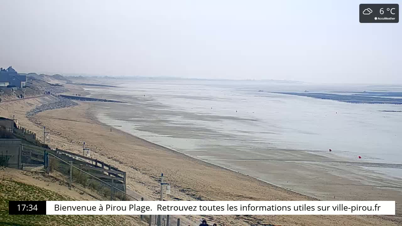A wide sandy beach stretches to a calm, light gray sea under an overcast sky.