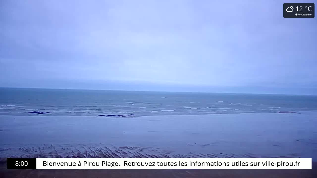 A mostly cloudy sky overlooks a calm ocean and wide, flat beach.