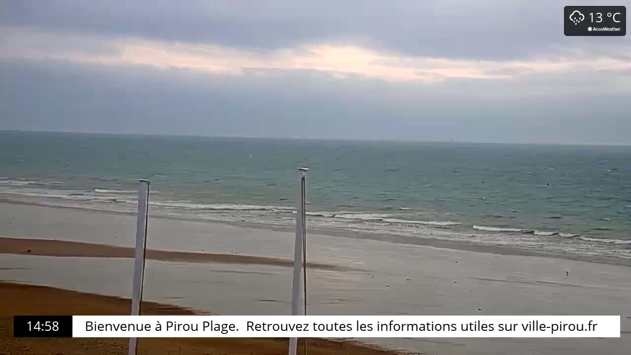 A wide shot of a beach with calm ocean waves under an overcast sky.