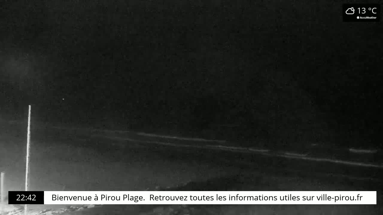 A nighttime, low-light view of a dark beach and ocean with calm waves under a cloudy sky at 13°C.