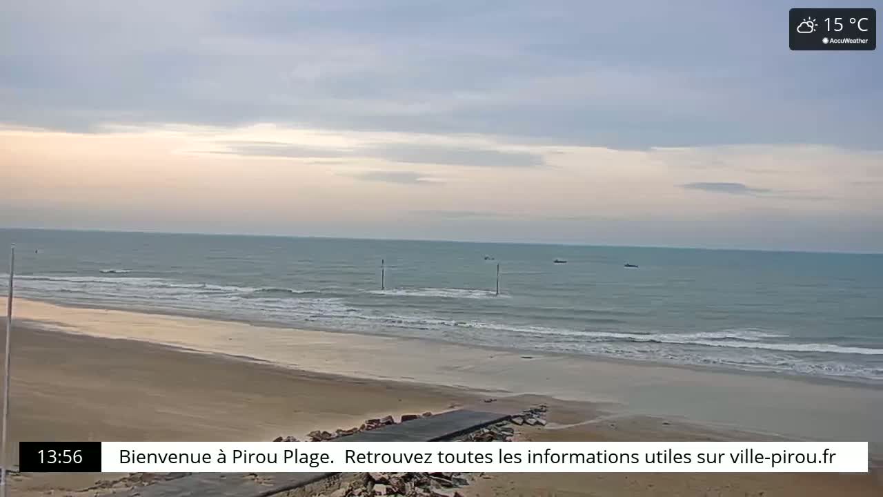 A sandy beach with gentle waves under a partly cloudy sky.