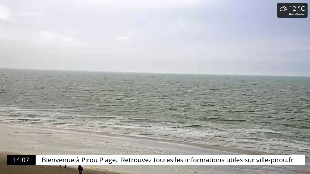 A wide shot of a beach with calm, gray-green ocean waves under an overcast sky.