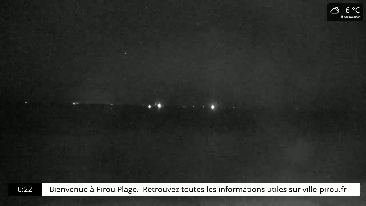 A nighttime, cloudy outdoor scene shows a line of distant lights on the horizon at 6 degrees Celsius.