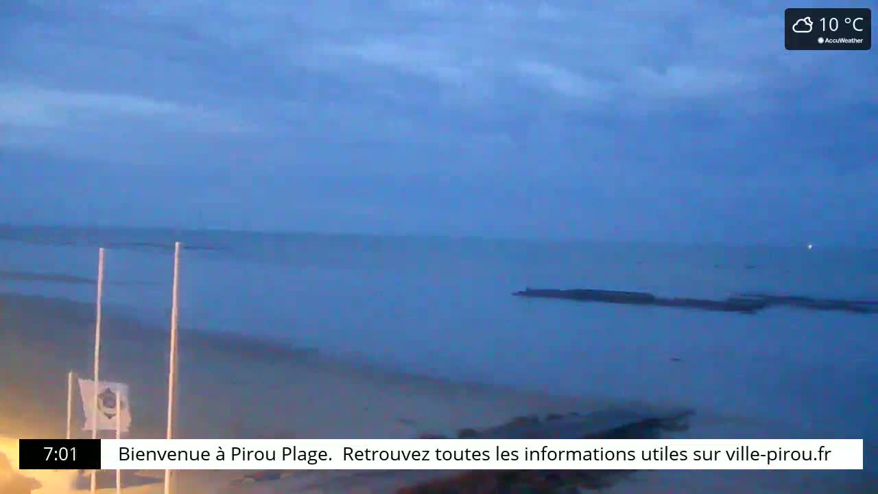 A sandy beach and calm ocean are visible under a partly cloudy, cool sky at dusk.