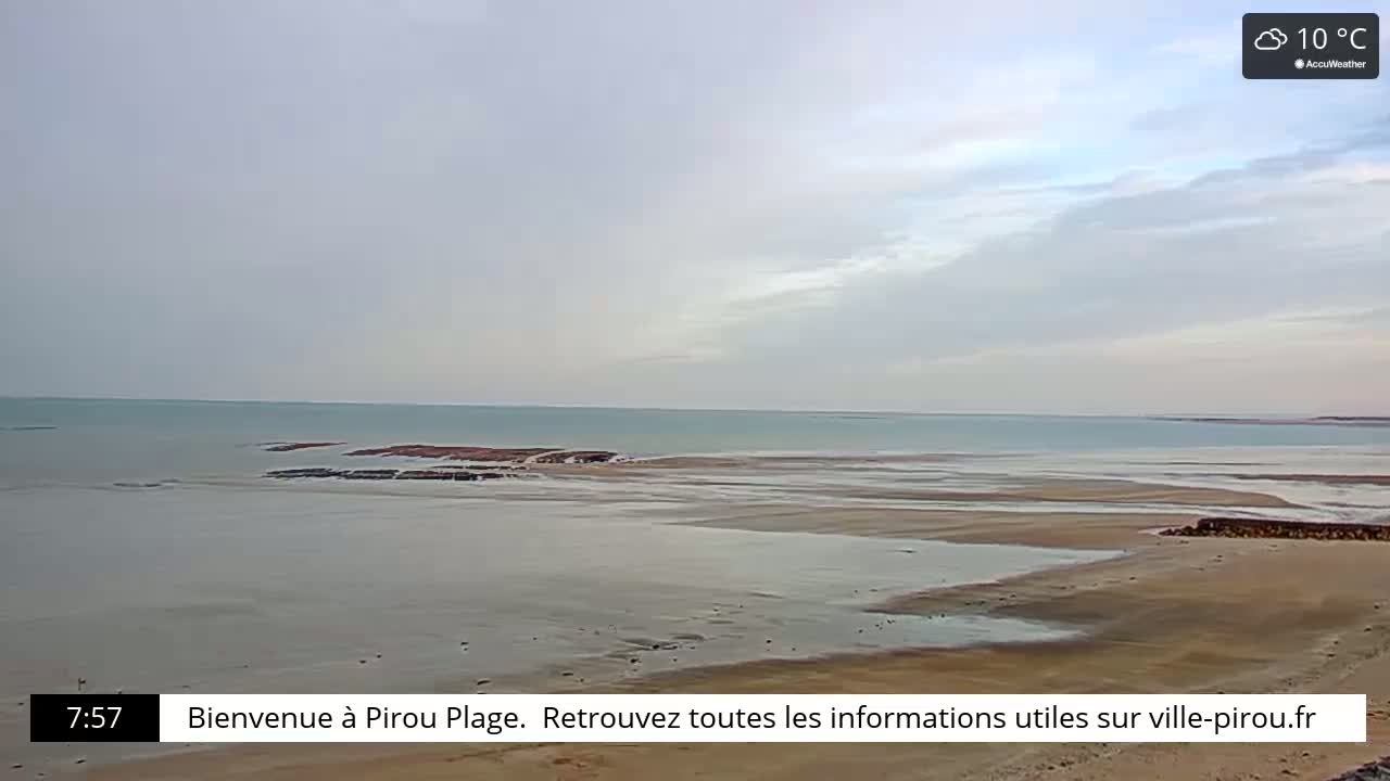A wide, flat beach stretches to a calm, light-green sea under a mostly cloudy, overcast sky.