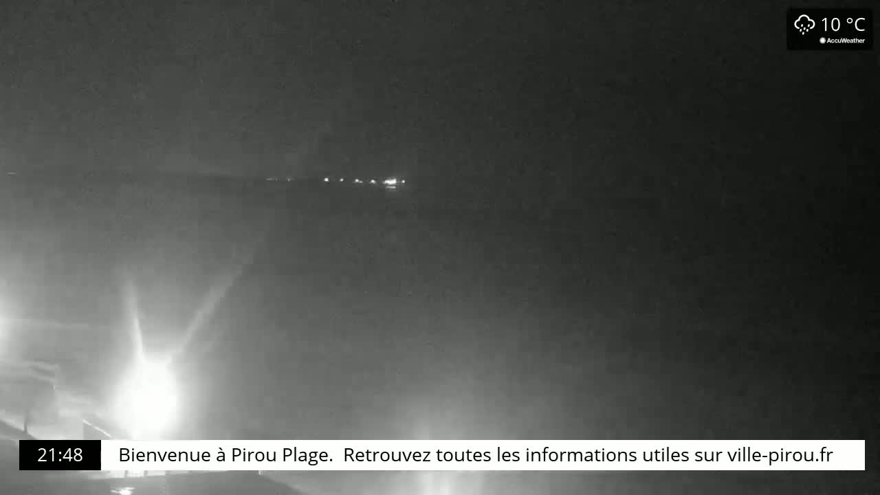 A nighttime, hazy view of a dimly lit coastline under a cloudy, 10°C sky.