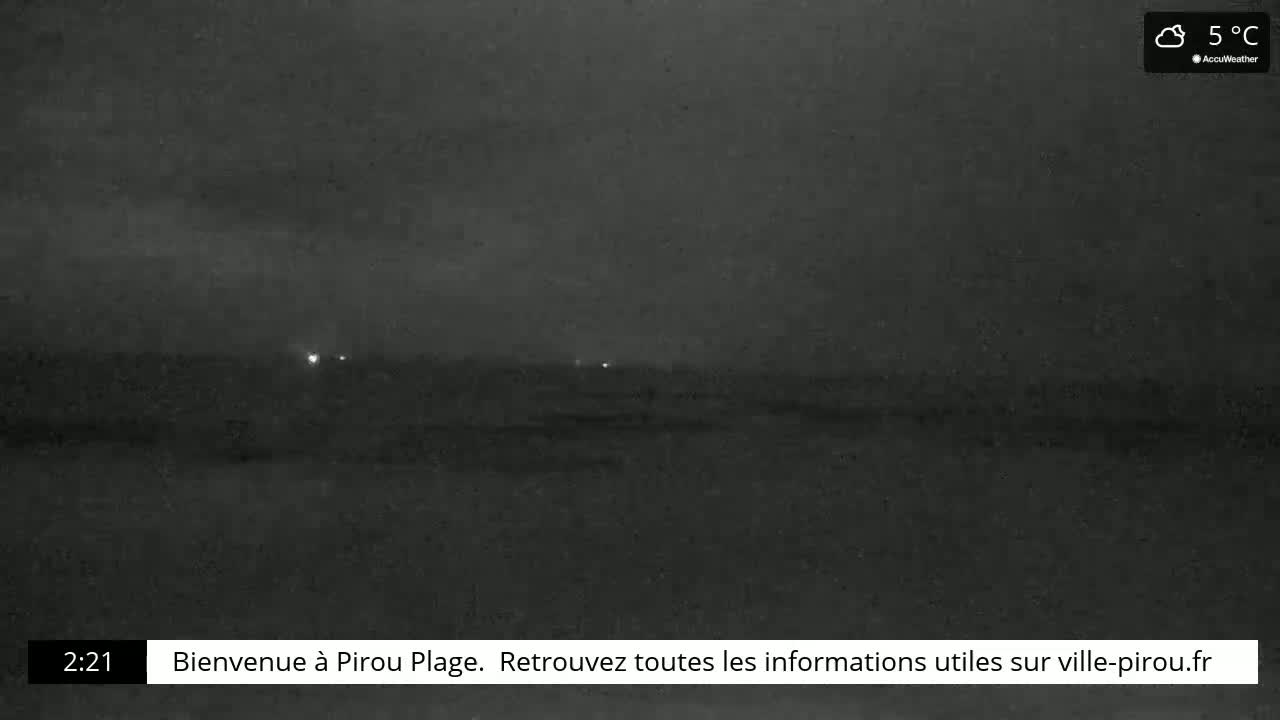 A dark, overcast nighttime scene shows a flat expanse of land with a few faint lights in the distance at 5°C.