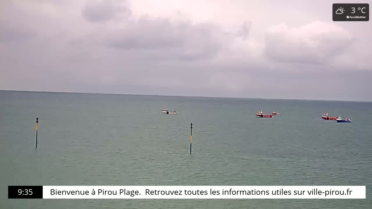 Several small fishing boats are visible on a calm, gray sea under a cloudy sky.