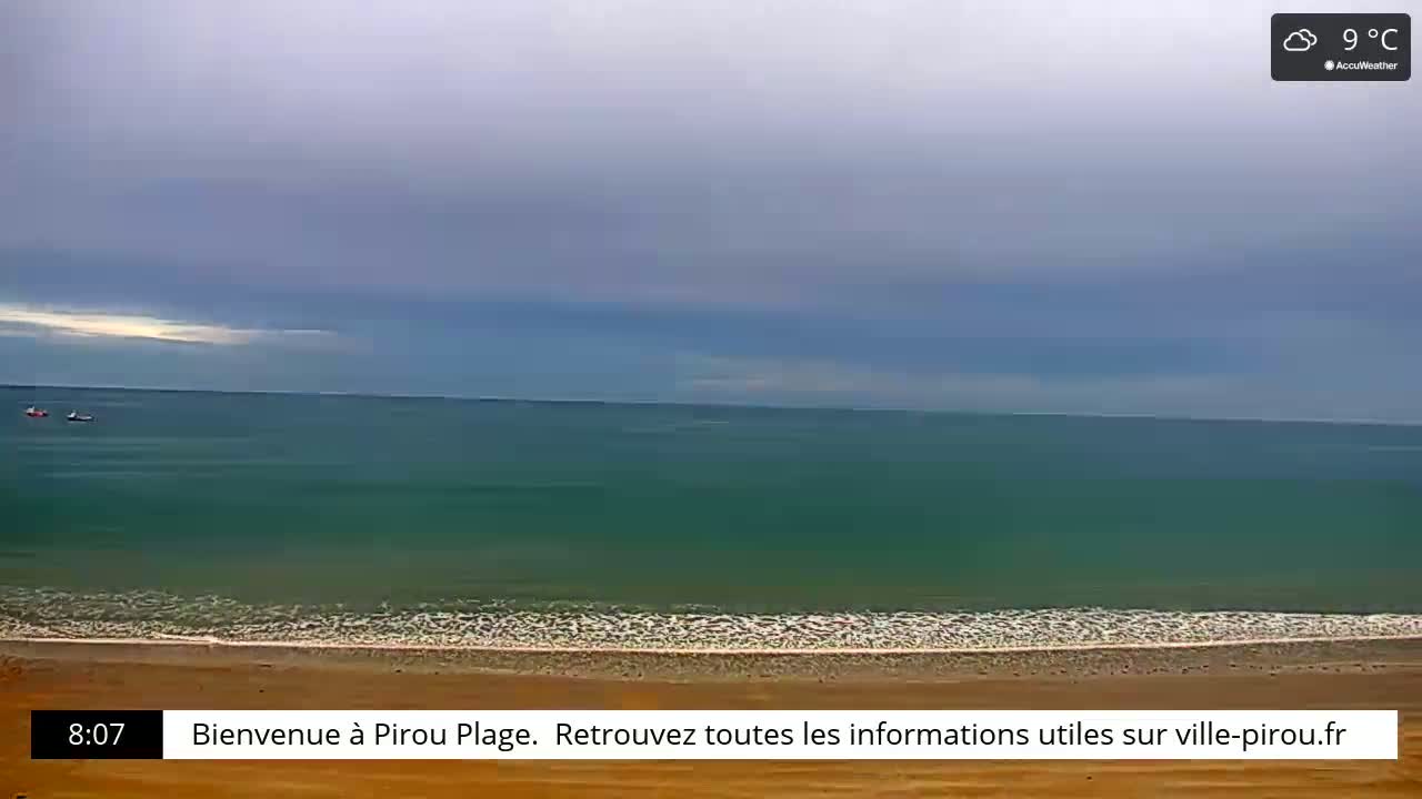 A sandy beach meets a calm, teal ocean under an overcast sky.
