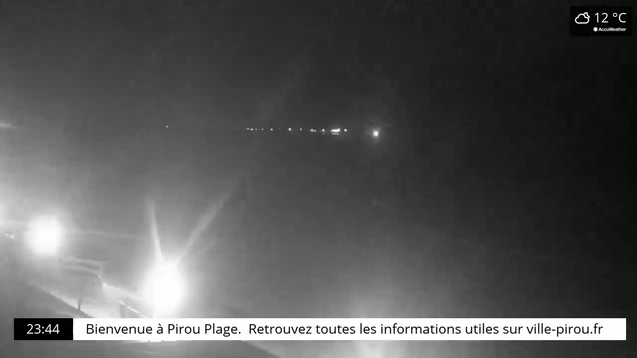A nighttime, hazy view of a road with distant lights and headlights of approaching vehicles in a 12°C environment.