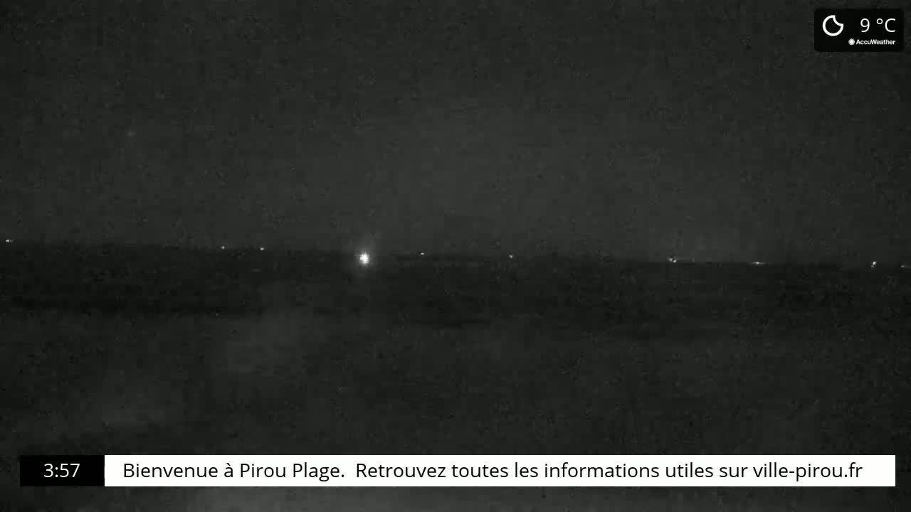 A nighttime, dark view of a flat landscape with a few distant lights visible under a clear, 9°C sky.
