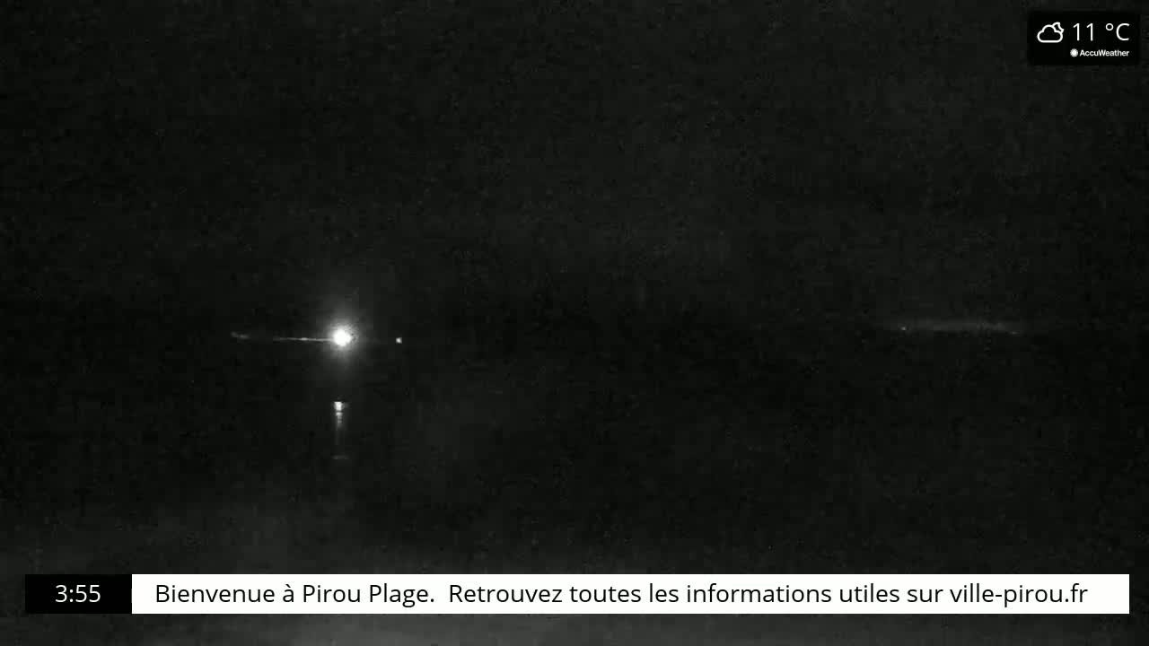 A nighttime scene shows a bright light in the distance over a dark body of water under a cloudy sky at 11°C.