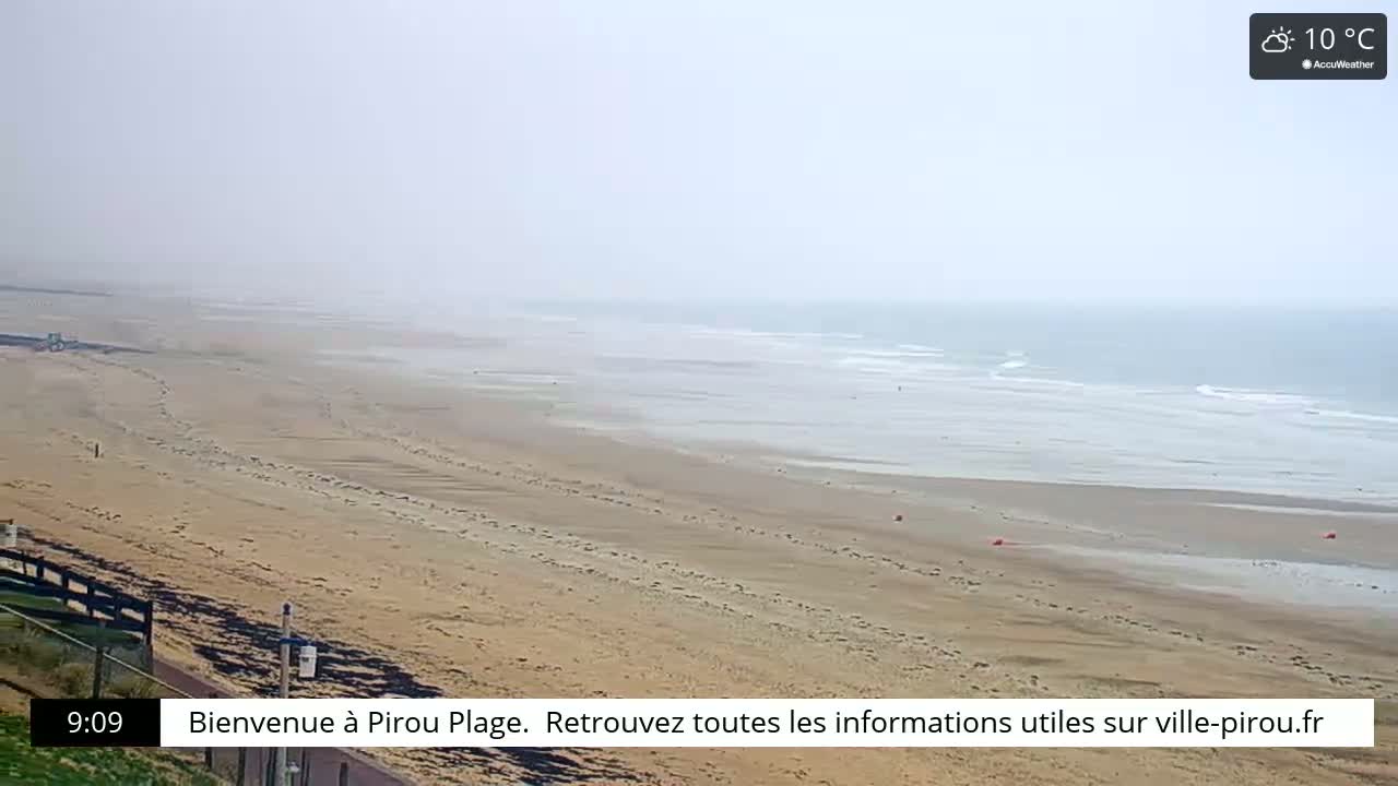 A hazy, sandy beach stretches to a calm ocean under a cloudy sky, with the temperature at 10 degrees Celsius.