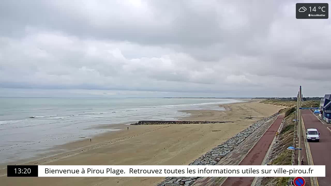 A wide sandy beach stretches along a calm ocean under a cloudy sky.