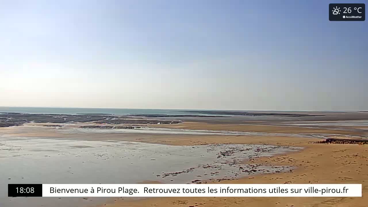 A wide sandy beach stretches to a calm ocean under a clear, sunny sky.