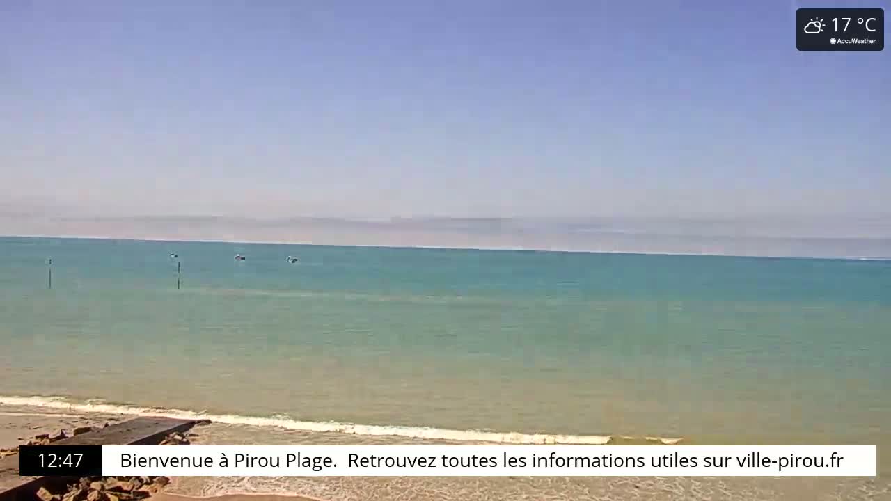 A mostly clear, sunny day with a calm, teal ocean meeting a sandy beach.
