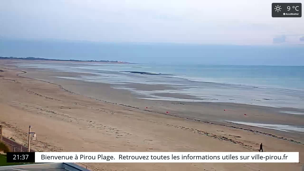 A sandy beach stretches to a calm, light-blue ocean under a sunny, 9°C sky.