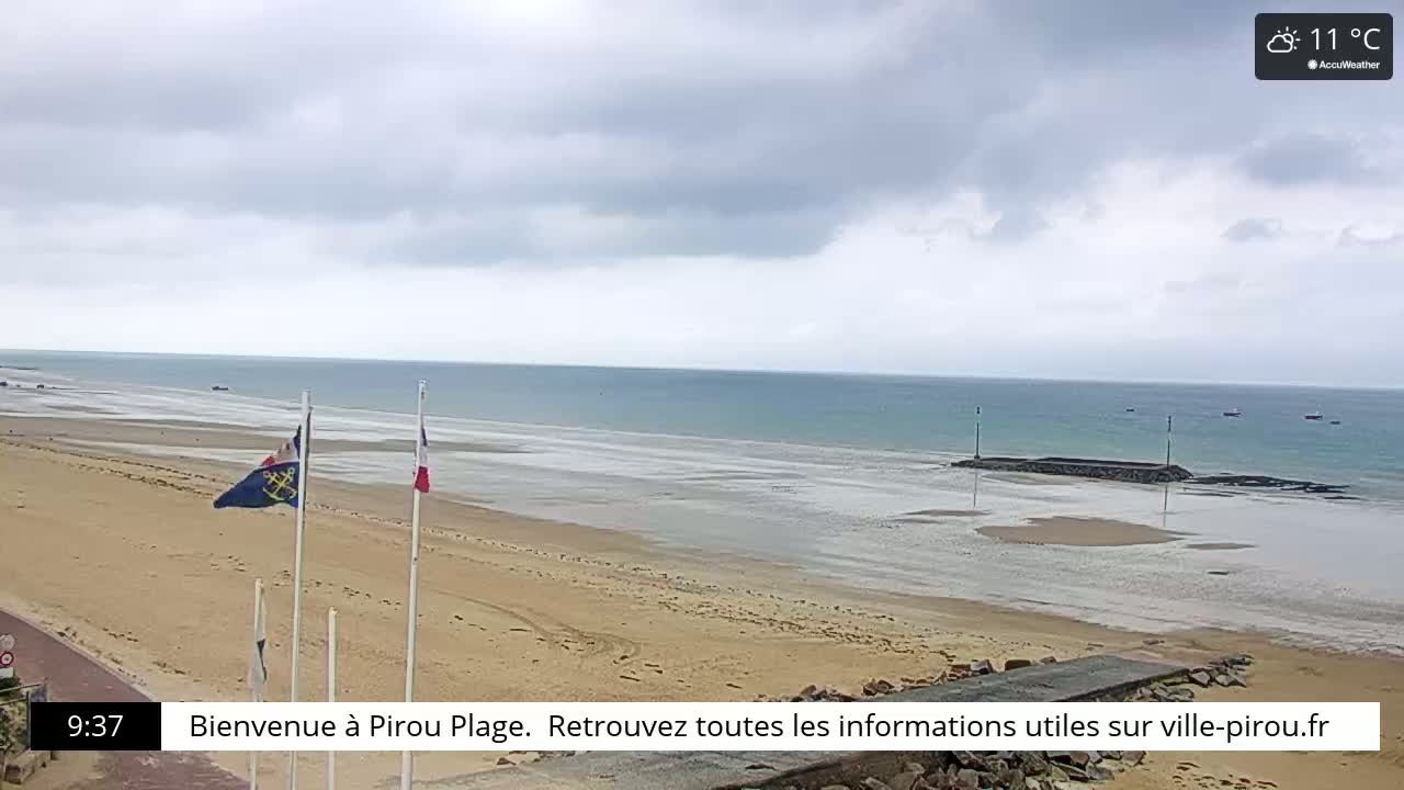 A sandy beach stretches to a calm, light-blue ocean under an overcast sky.