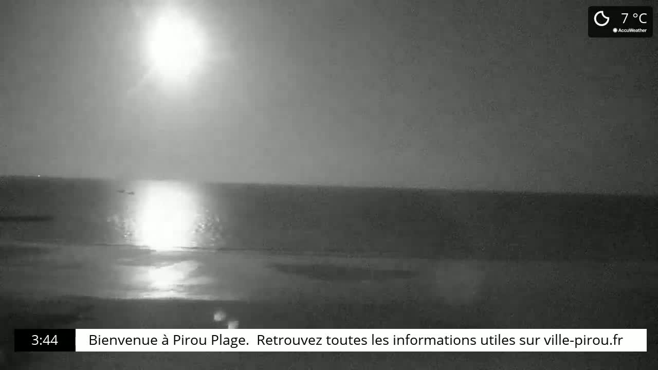 A bright light reflects off the dark ocean at night, under a 7°C sky.