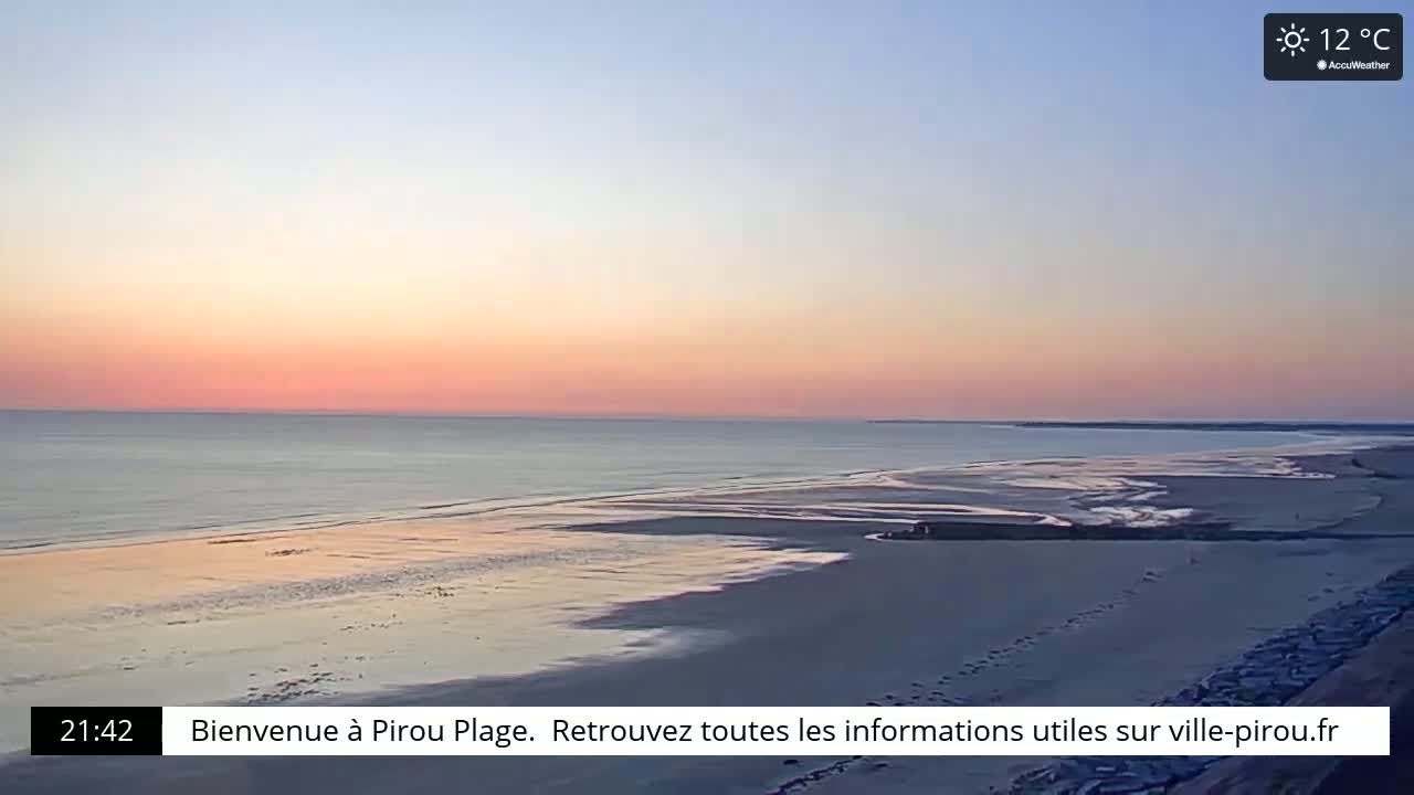 A wide, sandy beach stretches toward a calm ocean under a pale pink and orange sunset.