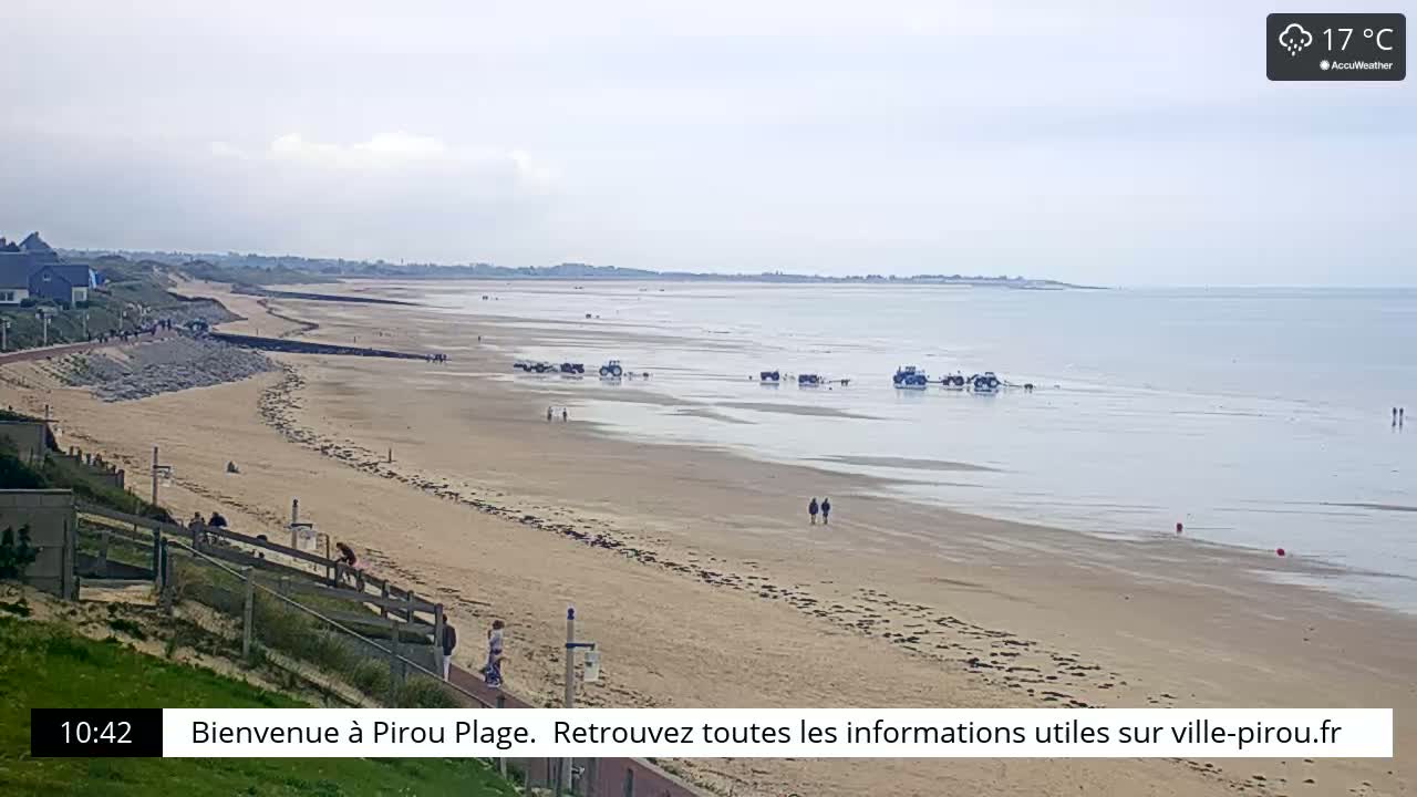 A long sandy beach stretches to a calm sea under a partly cloudy sky.
