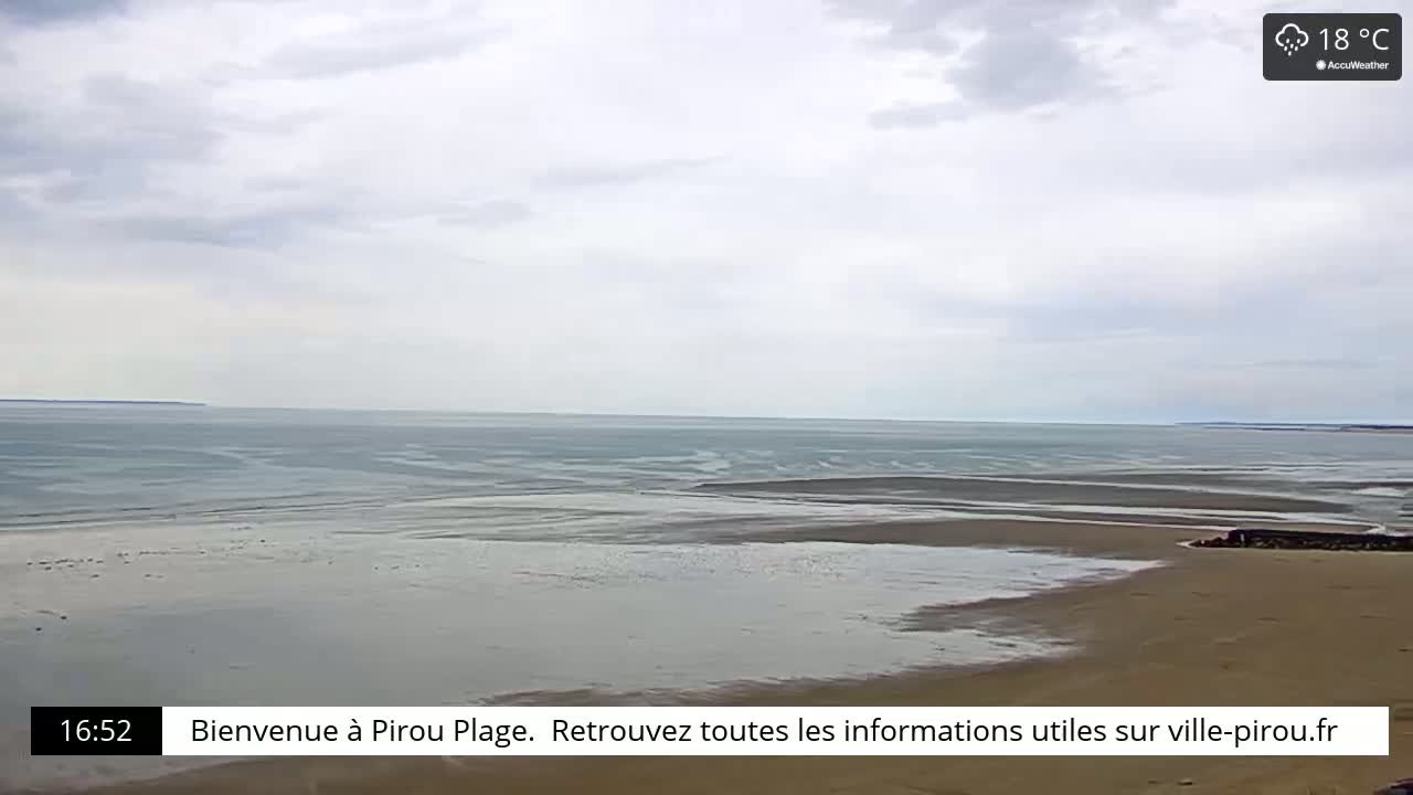 A mostly cloudy day reveals a wide sandy beach and calm ocean waters at low tide.