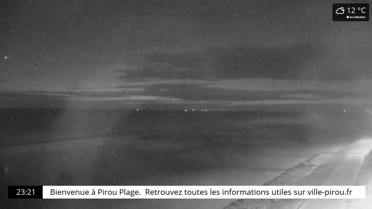 A nighttime view of a flat, dark landscape under a cloudy sky, with a few distant lights visible.