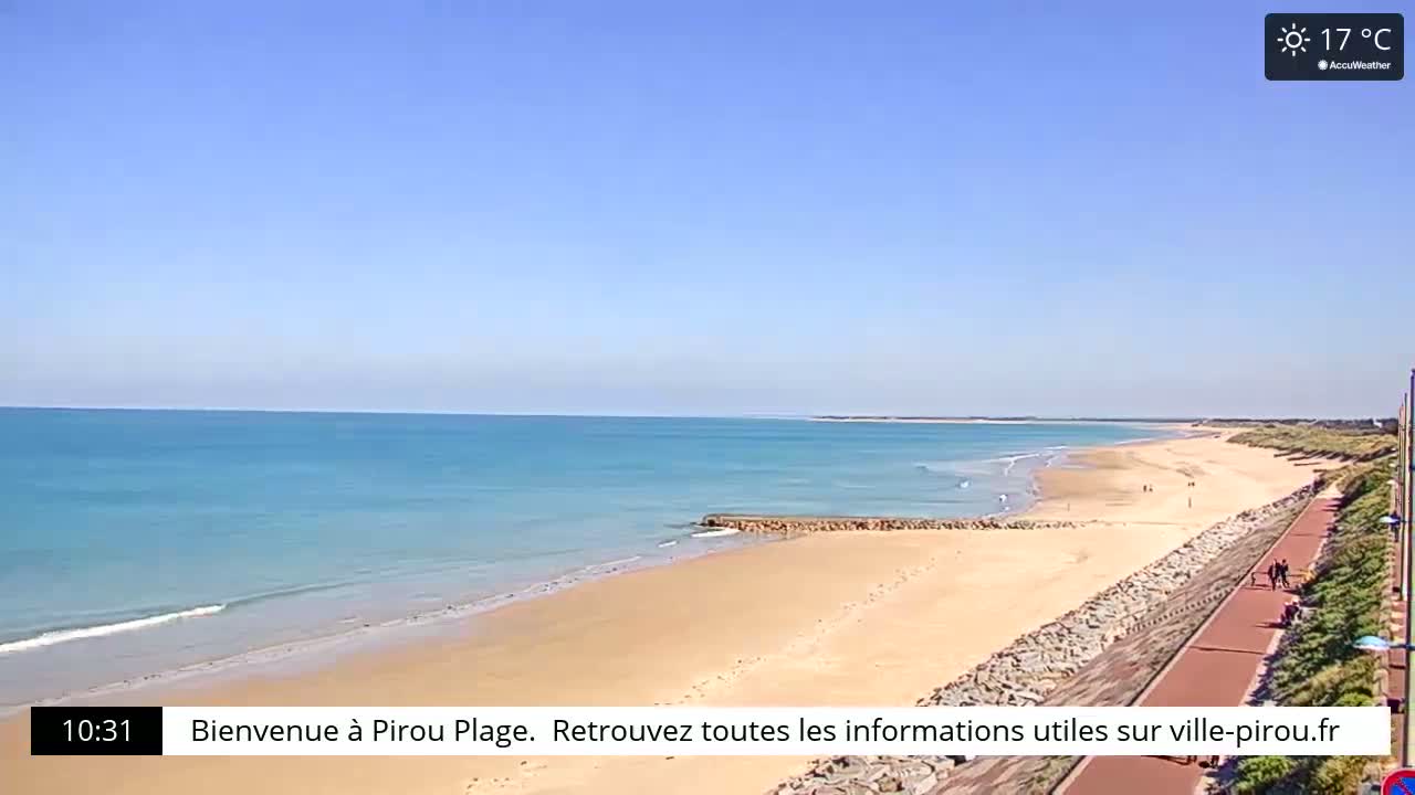 A long sandy beach stretches along a calm, turquoise ocean under a clear blue sky.