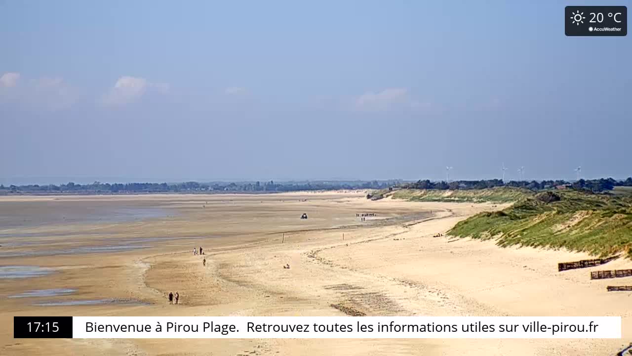 A wide, sandy beach stretches to a calm, wide body of water under a mostly sunny sky.