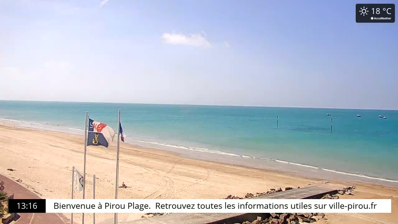 A sandy beach stretches along a calm, turquoise ocean under a clear, sunny sky.