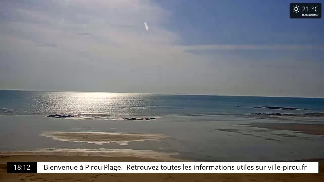 A calm, sunny ocean beach scene with a partly cloudy sky and a temperature of 21°C.