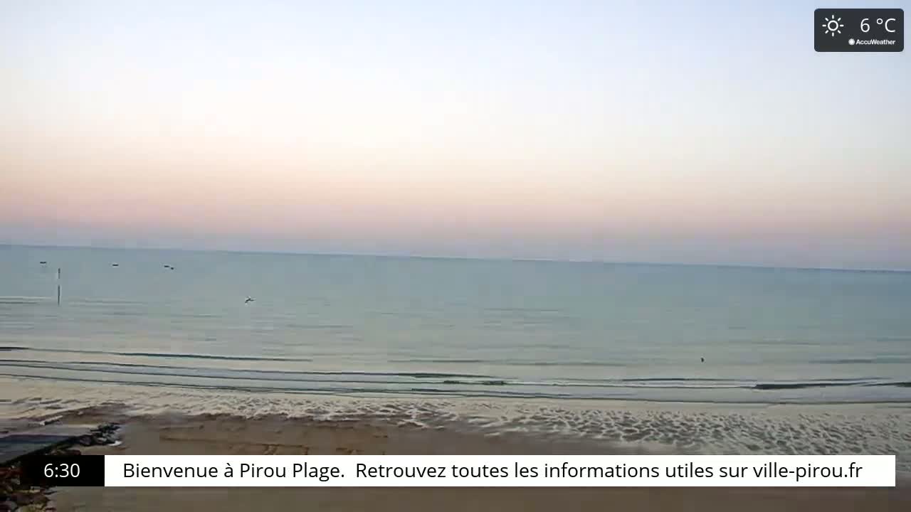 A calm, pale-pink sunrise illuminates a tranquil beach and a placid ocean under a clear sky, with the temperature at 6°C.