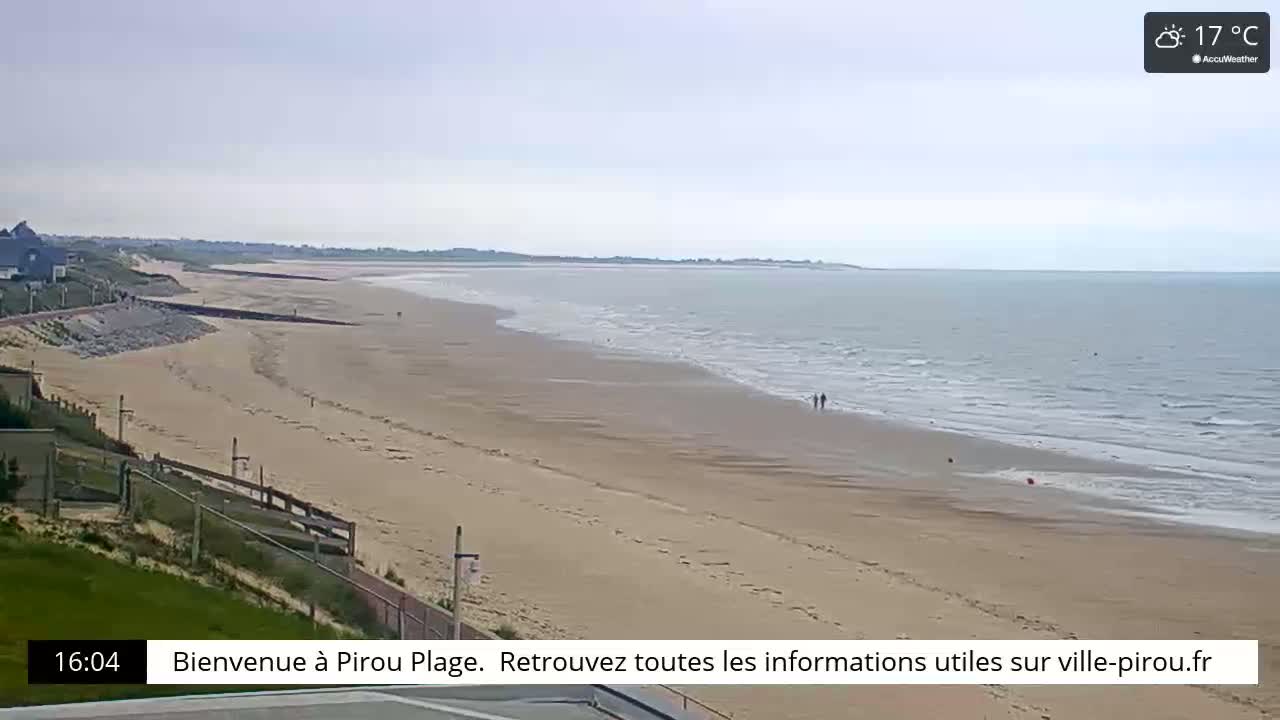 A long, sandy beach stretches to a calm, gray-blue ocean under a mostly cloudy sky.