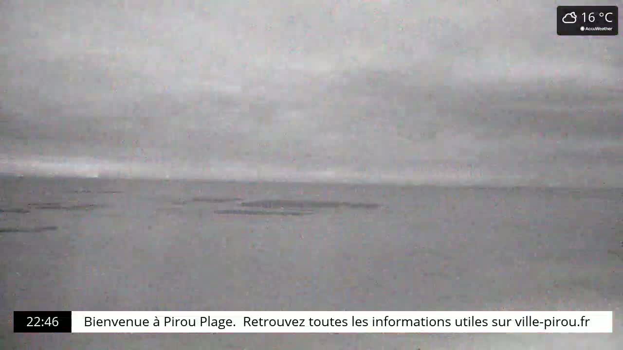 A mostly cloudy, overcast sky hangs over a calm body of water.