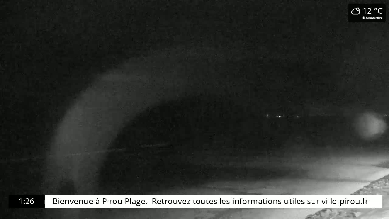 A nighttime, low-light view of a beach shows a dark, possibly cloudy sky at 12°C.
