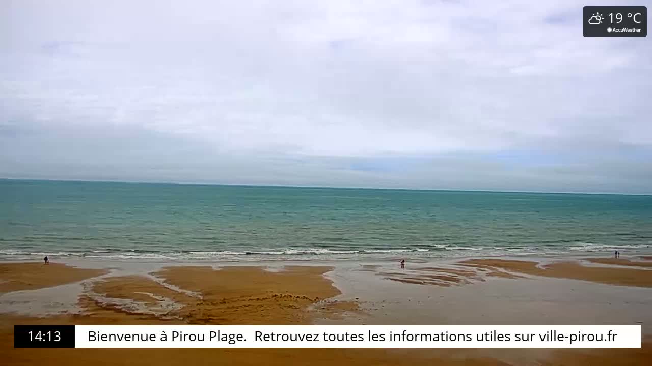 A wide sandy beach stretches towards a calm, teal ocean under a mostly cloudy sky.
