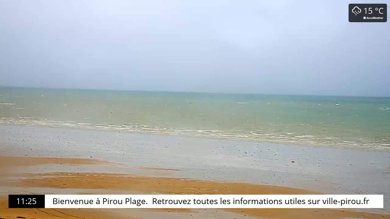 A sandy beach meets a calm, light-green sea under an overcast sky.