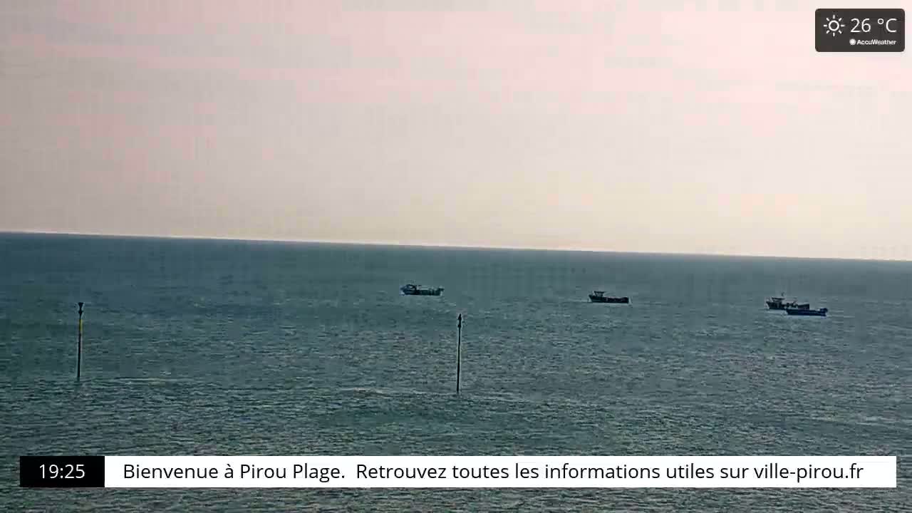 A calm sea with three small boats is visible under a clear, sunny sky, with a temperature of 26°C.