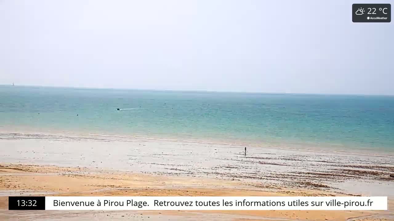 A sandy beach stretches to a calm, light-blue ocean under a hazy sky.