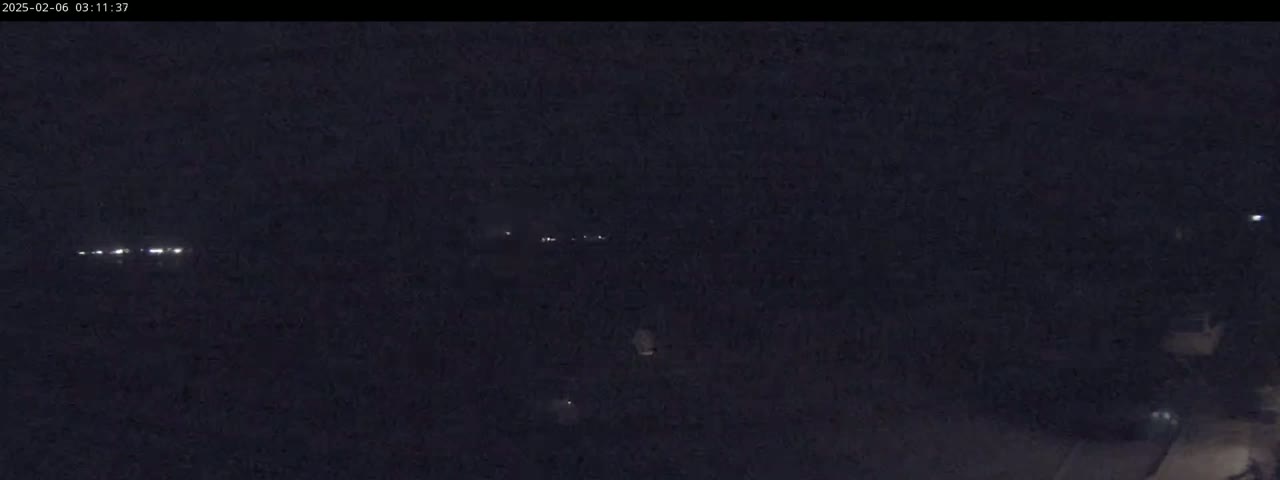 A dark, nighttime scene shows a few distant lights and a mostly obscured landscape.