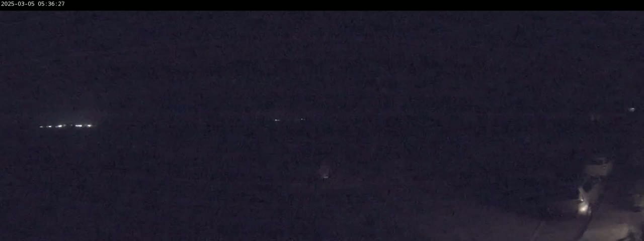 A nighttime, dark image shows a few distant lights in the upper-center and lower-right.
